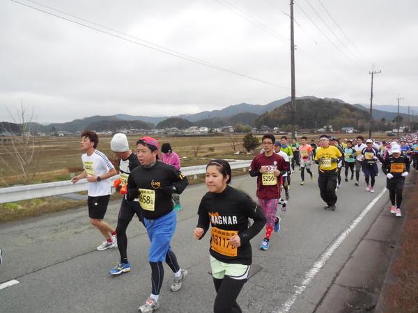 横には畑の広がった、すこし登りになっている道路を参加者たちが懸命に走っている写真